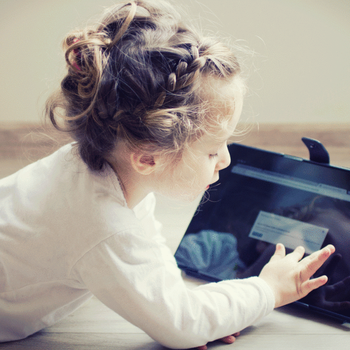 girl-playing-on-notebook-in-stand-on-floor
